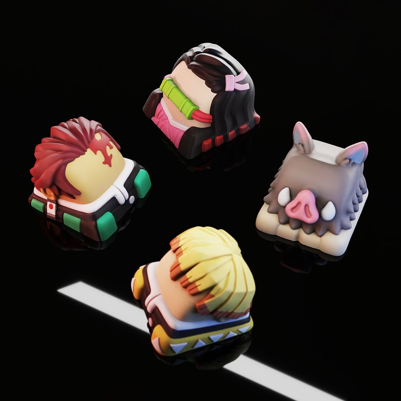 May include: Four colorful keycaps featuring characters from the anime Demon Slayer. The keycaps are made of plastic and have a 3D design. The keycaps are in the colors of pink, green, yellow, and brown.
