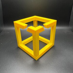 May include: A yellow impossible cube sculpture, a 3D-printed optical illusion. The cube appears to defy the laws of physics with its interconnected, yet seemingly impossible, structure. The sculpture is a bright, solid yellow color.