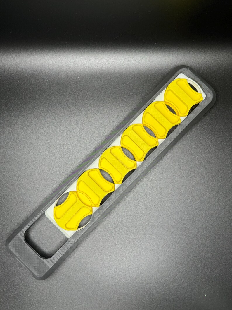 May include: A black and white plastic tool with a handle and a row of yellow, circular cutouts.