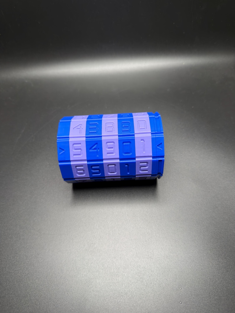 May include: A blue and purple combination lock with numbers. The cylindrical lock has a series of numbers and squares in blue and purple. The numbers are white. The lock is on a black surface.