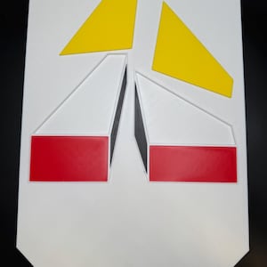May include: A geometric wall art piece featuring a white background with yellow, red, and black accents. The design includes two yellow triangles at the top and two red rectangles at the bottom, with black lines.