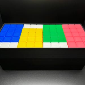 May include: A set of four colorful square tiles, each with a different color: blue, yellow, green, and pink. The tiles are arranged in a row, with a white border around each tile.