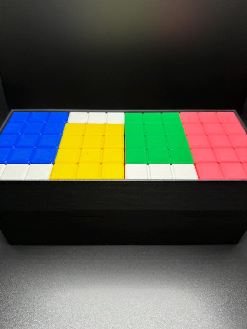 May include: A set of four colorful square tiles, each with a different color: blue, yellow, green, and pink. The tiles are arranged in a row, with a white border around each tile.