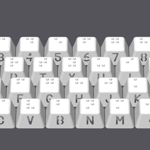 May include: A white keyboard with braille markings on each key. The keys are arranged in a standard QWERTY layout. The keyboard includes numbers, letters, punctuation marks, and function keys.