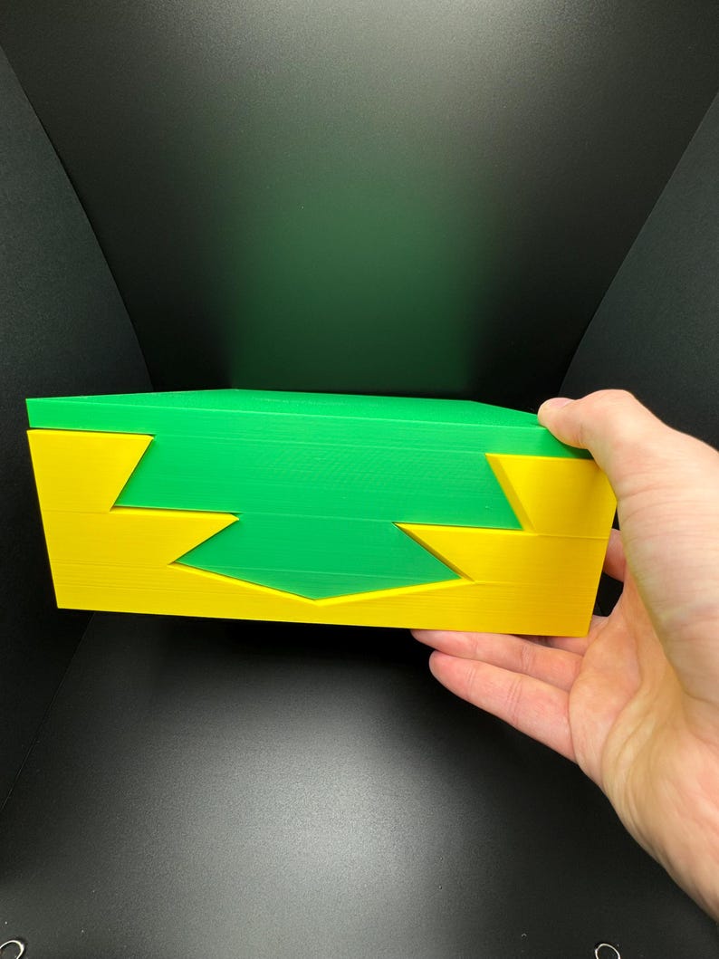 May include: A green and yellow interlocking puzzle made of three pieces. The puzzle is made of a hard plastic material.