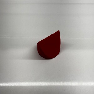 May include: A red, triangular-shaped makeup sponge.