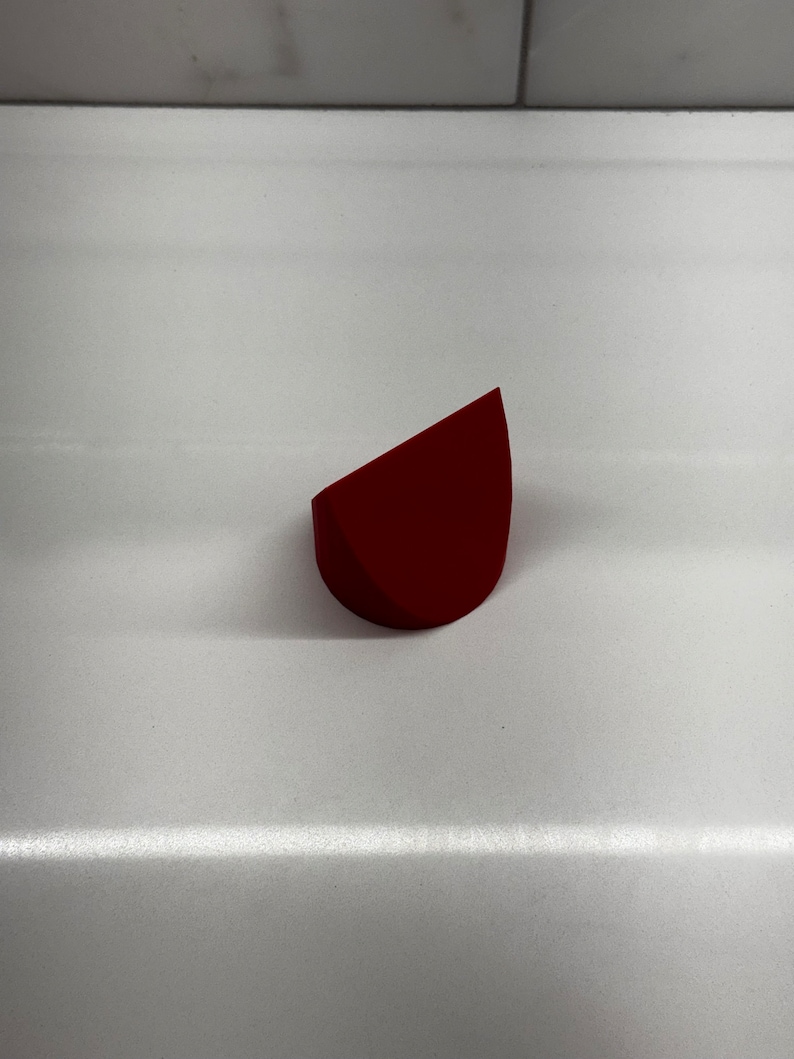 May include: A red, triangular-shaped makeup sponge.