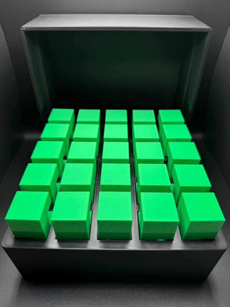 May include: A black box with a lid open, revealing a grid of 36 bright green cubes.