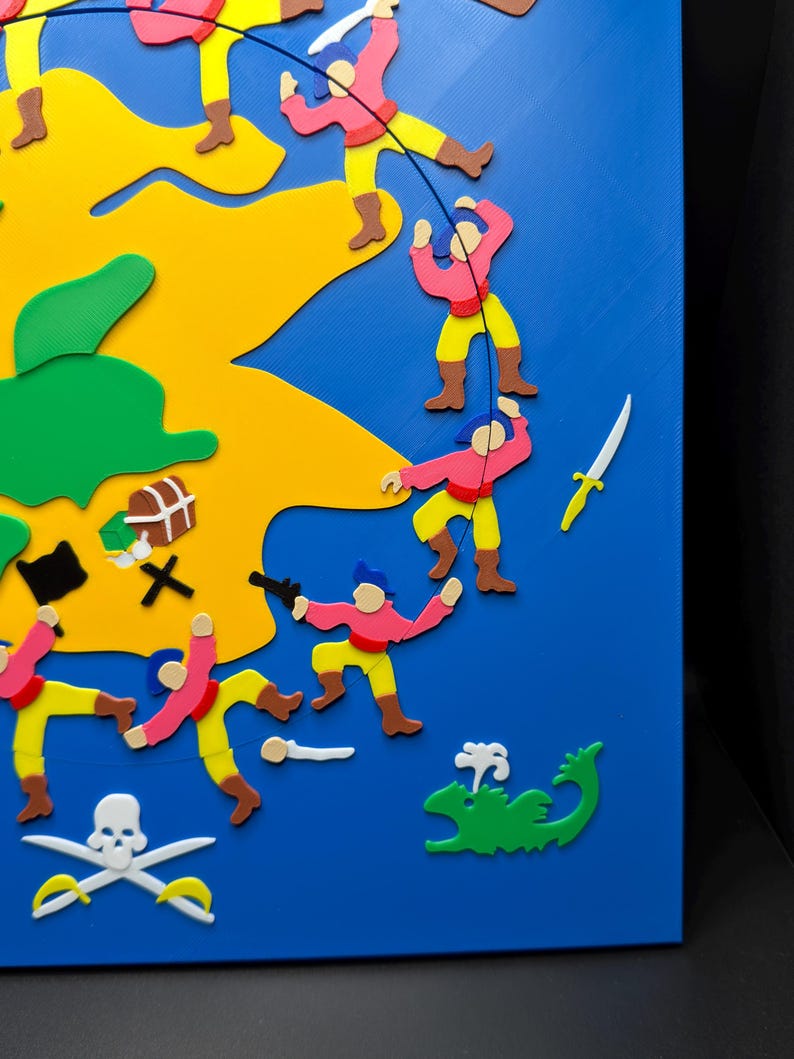May include: A colorful, 3D-printed pirate-themed artwork. The piece features a blue background with a yellow island, green sea monster, and various pirate figures in pink, yellow, and brown. Includes a skull and crossbones, crossed swords, and a treasure chest.
