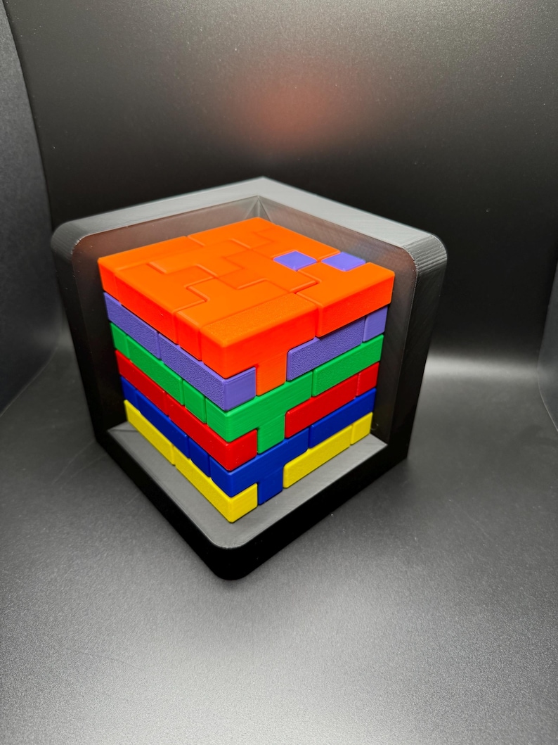 May include: A colorful block puzzle with a variety of shapes and colors. The puzzle is assembled in a square frame and is made of plastic.