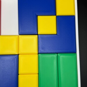 May include: A puzzle with blue, yellow, and green square tiles arranged in a grid pattern. The tiles are arranged in a way that creates a geometric design.