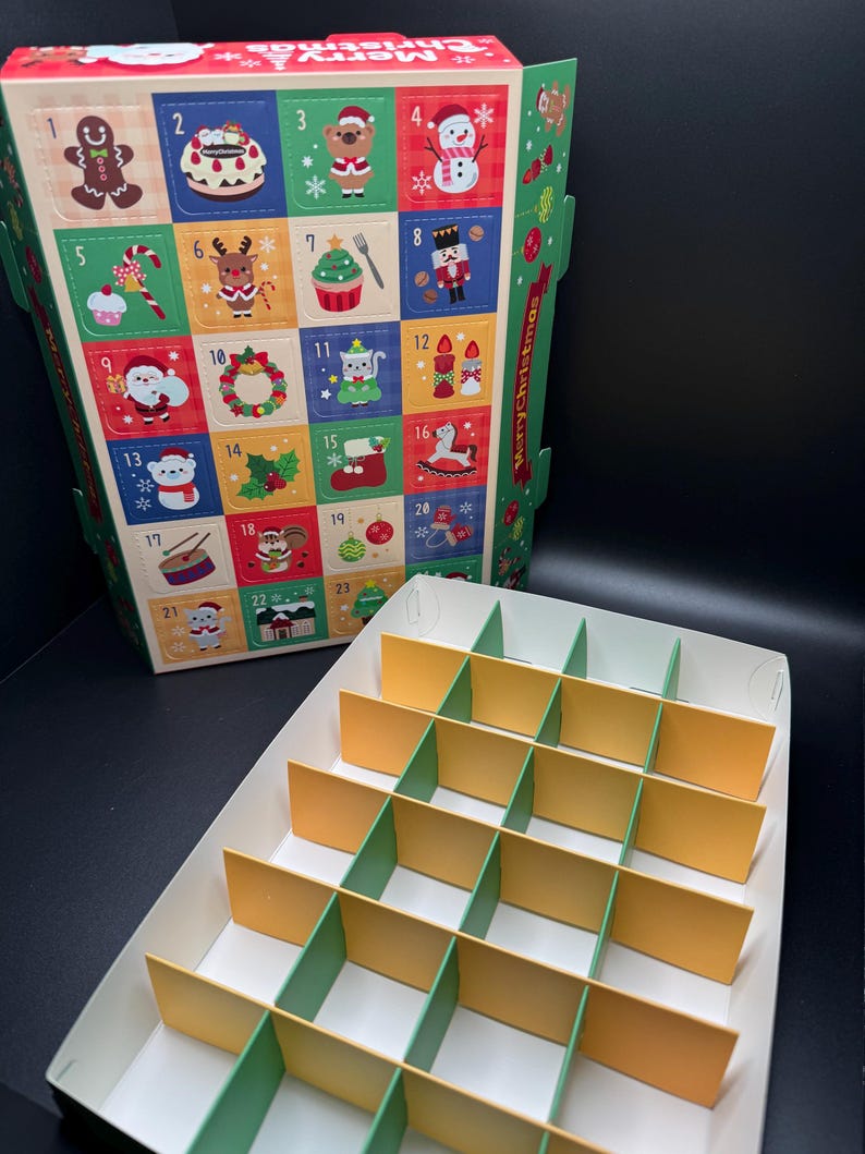 May include: A Christmas advent calendar box with colorful squares featuring festive illustrations and numbers. The box is open, revealing a compartmented interior for treats. The words "Merry Christmas" are printed on the side.