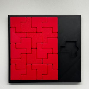 May include: A red and black puzzle game with a square grid of red tiles and a black frame. The game includes a black silhouette of a car on the right side of the frame.