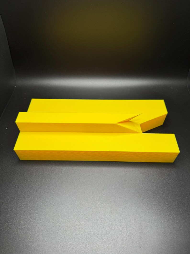 May include: A yellow plastic object with a rectangular shape and a slight bend in the middle.