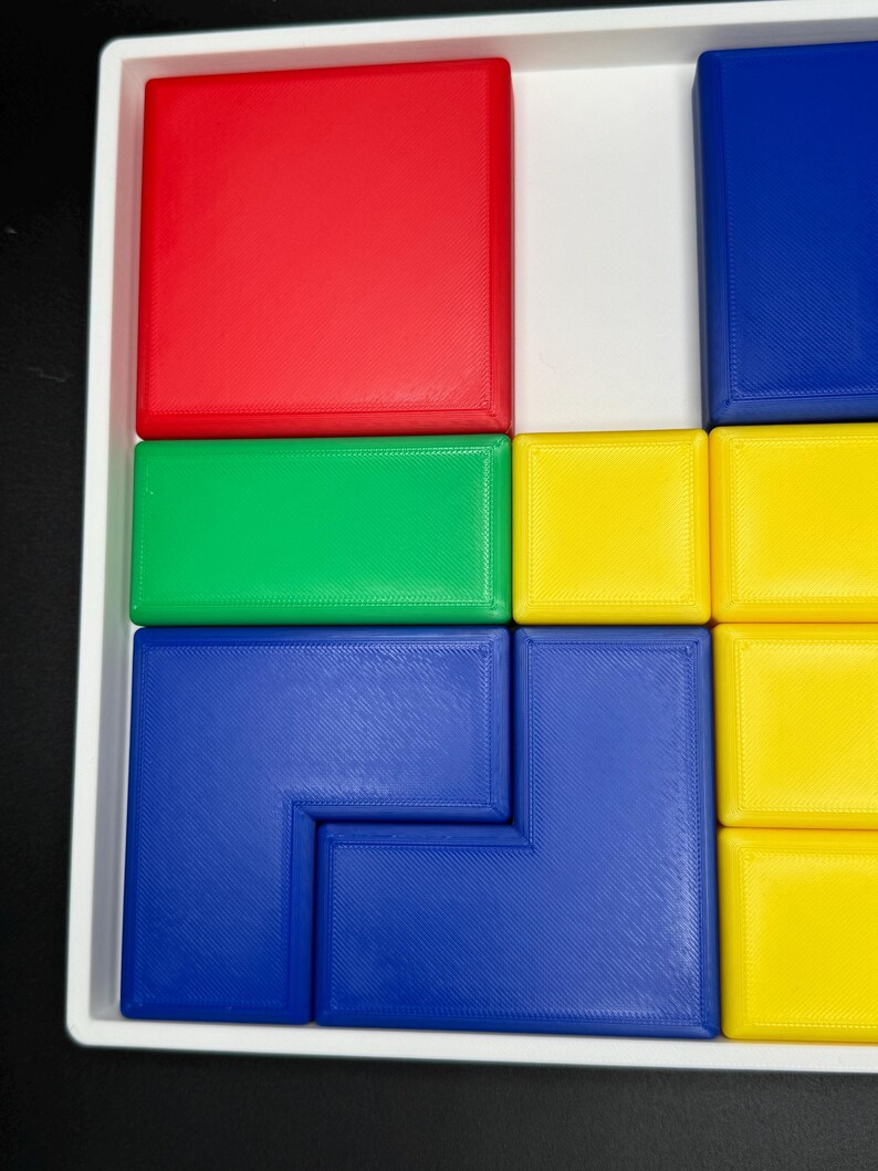 May include: A puzzle with a variety of colored blocks. The blocks are arranged in a grid pattern, with red, green, yellow, and blue blocks. The puzzle is made of plastic and has a smooth, glossy finish.