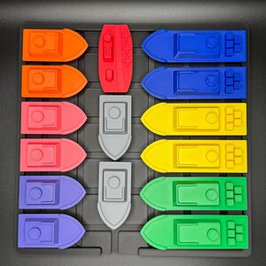 Op de afbeelding: Een spelbord met 10 rijen kleurrijke boten. De boten zijn in een rasterpatroon gerangschikt. De boten zijn gemaakt van plastic en zijn in verschillende kleuren, waaronder rood, oranje, roze, geel, groen, blauw en grijs.