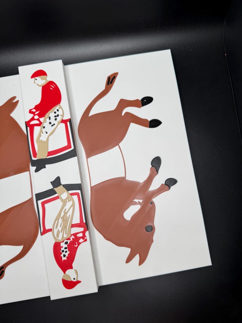 May include: A set of three white wooden tiles with a red, white, and black illustration of a jockey riding a brown horse. The horse is in a jumping position with its legs in the air.