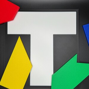 May include: A white T-shaped puzzle piece with four different colored puzzle pieces surrounding it. The pieces are red, yellow, green, and blue.