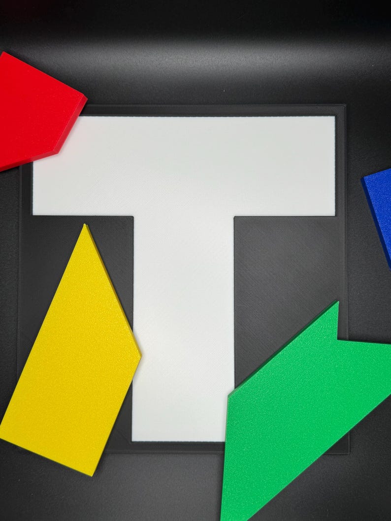 May include: A white T-shaped puzzle piece with four different colored puzzle pieces surrounding it. The pieces are red, yellow, green, and blue.