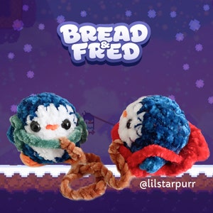 May include: Two blue and white penguin plush toys with green and red accents are connected by a brown rope. The penguins are wearing scarves and hats. The text "Bread & Fred" is in the background.