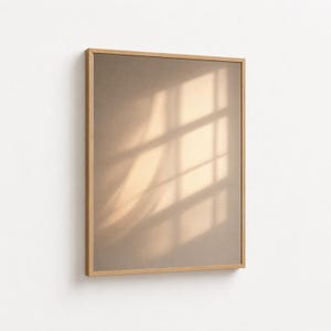 Op de afbeelding: Een rechthoekig, ingelijst kunstwerk met een lichtbruine achtergrond. Het kunstwerk wordt verlicht door de schaduwen van een raam, waardoor een patroon van lijnen en vormen ontstaat. Het frame is gemaakt van lichtgekleurd hout.