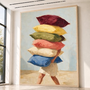 May include: A large framed oil painting depicting a figure carrying a tall stack of six rectangular pillows in shades of deep red, yellow, olive green, coral pink, cream, and blue, wearing a simple light-colored skirt against a pale blue background.