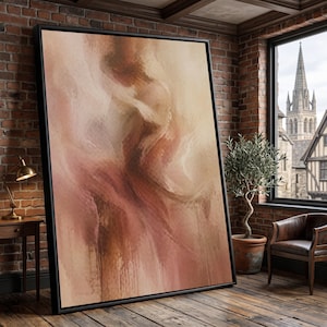 Könnte beinhalten: Großer, gerahmter Kunstdruck mit abstrakter Kunst. Das Kunstwerk zeigt eine Mischung aus warmen Farben, darunter Beige-, Rosa- und Brauntöne, mit einem strukturierten, pinselstrichartigen Aussehen. Das Gemälde lehnt an einer Backsteinmauer in einem Raum.
