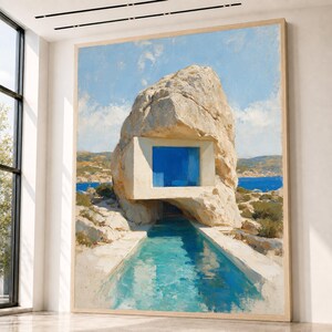 May include: A large rectangular wall art print featuring a painting of a modern architectural structure built into a massive beige rock formation, with a bright blue window, a turquoise swimming pool, and a coastal landscape under a blue sky.