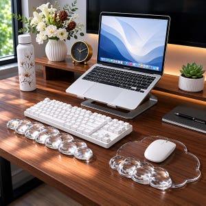 May include: A modern workspace featuring a white keyboard, mouse, and cloud-shaped mousepad. A laptop sits on a silver stand, with a small succulent, a clock, and a floral water bottle. The desk is made of dark wood.