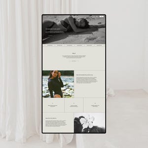 May include: A black and white website interface displayed on a screen, featuring a hero image of a person on a beach, text sections titled Transcend Your Limits, About, and Dive into Embodied Empowered Living, alongside a photograph of a flower.