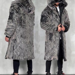 May include: A long, grey and black faux fur coat featuring a large hood, a front zipper closure, and a black utility-style pocket on the upper sleeve. The coat has a thick, textured pile and is worn over black pants and black athletic sneakers.