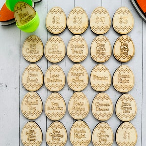 May include: Wooden Easter eggs with different rewards written on them, including "New Outfit", "$2", "$3", "$4", "$5", "25 Cents", "50 Cents", "Sweet Treat", "Day With Mom", "Day With Dad", "New Book", "Later Bedtime", "Reward of Choice", "Picnic", "Game Night", "Small Toy", "Fun Activity", "New Game", "Choose Dinner", "Extra Screen Time", "One Hour of Video Games", "New Coloring Book", "Movie Night", "No Chore Day", and "$1".