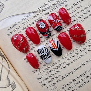 Può includere: Nail art rossa e bianca con design a tema Harry Potter. Le unghie sono decorate con glitter, un treno Hogwarts Express, una sciarpa della casa di Hogwarts e le parole "Harry Potter".