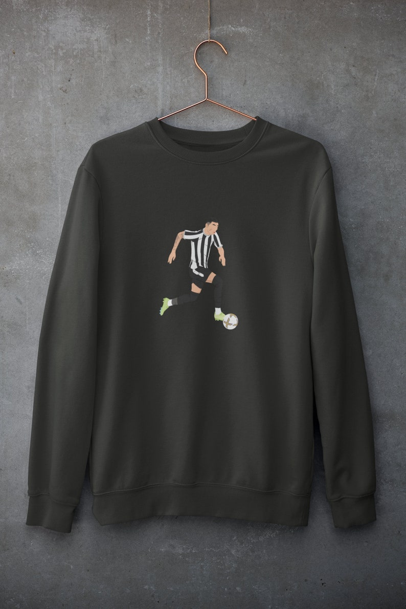 Puede incluir: Una sudadera gris oscuro con una ilustraci&oacute;n en blanco y negro de un jugador de f&uacute;tbol que dribla el bal&oacute;n.