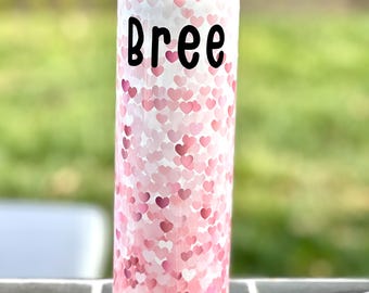 以下が含まれることがあります： ピンクのハート柄の白いタンブラーに、黒い文字で「Bree」と印刷されています。