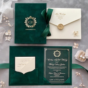 Könnte beinhalten: Smaragdgrünes Hochzeitskarten-Set mit goldenen Akzenten. Das Set beinhaltet eine samtartige Einladung, eine Antwortkarte und einen Umschlag. Die Einladung zeigt die Initialen "CD" und das Datum "13. Dezember 2024". Ein grünes Band hält die Einladung zusammen.