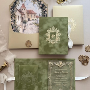 May include: Elegant wedding invitation suite featuring a castle illustration, olive green velvet, and gold accents. Includes a pocketfold, invitation card, and envelope with a wax seal. The suite is tied with a white ribbon.