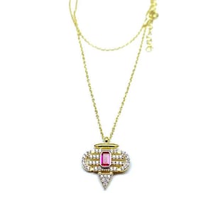 Może przedstawiać: Złoty naszyjnik z łańcuszkiem i geometrycznym wisiorem z różowym kamieniem szlachetnym otoczonym przez przezroczyste kamienie.