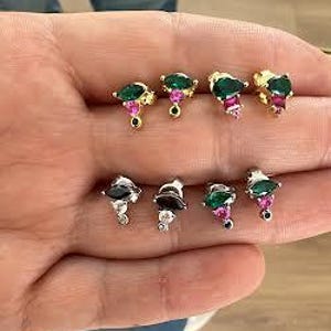May include: A set of six earrings with a teardrop-shaped green and black stone and a smaller pink stone. The earrings are on a white background.