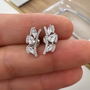 May include: A pair of silver earrings with a leaf design and clear cubic zirconia stones.