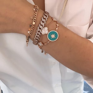 Pu&ograve; includere: Un set di quattro braccialetti in oro con dettagli in diamanti. I braccialetti presentano una variet&agrave; di ciondoli, tra cui stelle, un quadrifoglio e una grande stella con un centro turchese.