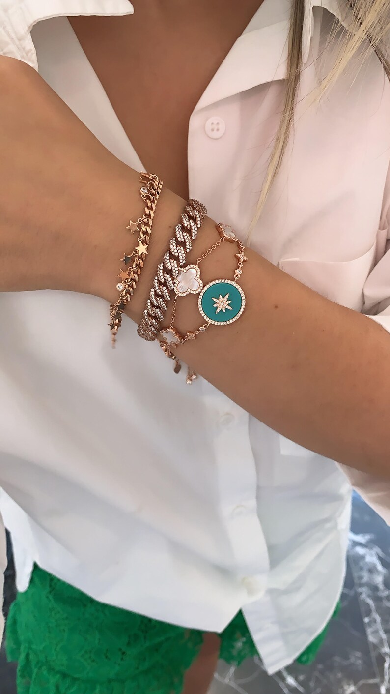 Pu&ograve; includere: Un set di quattro braccialetti in oro con dettagli in diamanti. I braccialetti presentano una variet&agrave; di ciondoli, tra cui stelle, un quadrifoglio e una grande stella con un centro turchese.
