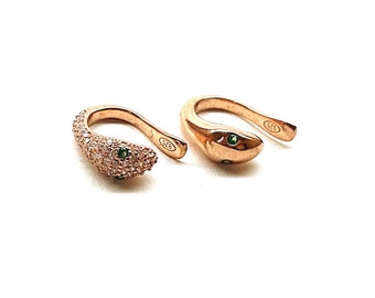 May include: A pair of rose gold snake ear cuffs with green gemstones and clear cubic zirconia stones. The ear cuffs are marked with "925" on the back.