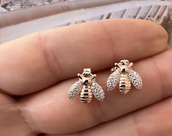 Op de afbeelding: Een paar gouden bijen oorbellen met heldere zirkonia stenen. De oorbellen zijn klein en delicaat, en ze zouden een geweldig cadeau zijn voor iemand die van bijen houdt.