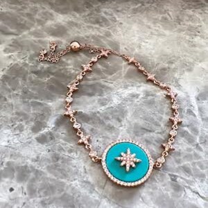 Pu&ograve; includere: Un braccialetto in oro rosa con un ciondolo turchese che presenta un design a stella scintillante. Il braccialetto &egrave; realizzato con una catena delicata con piccole pietre trasparenti.