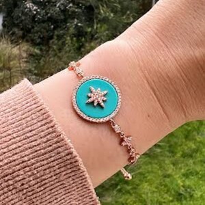 Pu&ograve; includere: Un braccialetto in oro rosa con un ciondolo a forma di stella turchese. Il ciondolo &egrave; circondato da strass trasparenti.