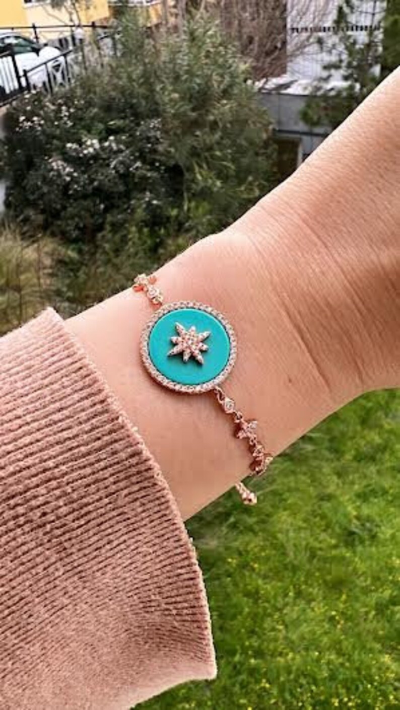 Pu&ograve; includere: Un braccialetto in oro rosa con un ciondolo a forma di stella turchese. Il ciondolo &egrave; circondato da strass trasparenti.