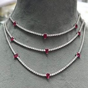 May include: A layered necklace with three strands of small, clear stones and red heart-shaped stones.