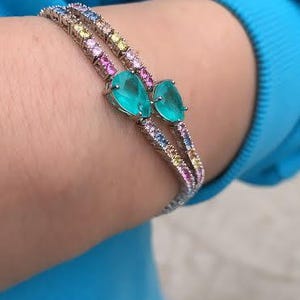 Può includere: Due braccialetti con pietre color arcobaleno e pietre turchesi a forma di lacrima.