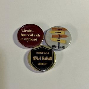 May include: Three circular pin-back buttons. One is dark red with the text Broke but real rich in my head. Another is light gray with yellow and orange directional signs reading YOU'RE GONNA GO FAR and NOAH KAHAN. The third is a black shield on gold with I CRIED AT A NOAH KAHAN CONCERT.